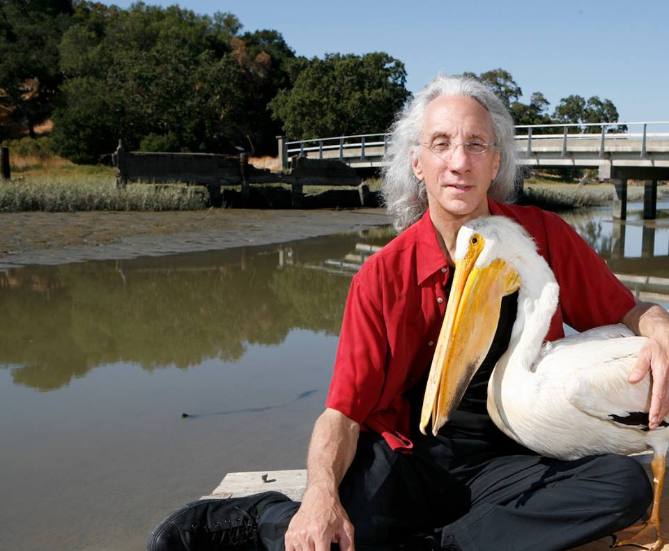 Rob Brezsny photographed at the water&rsquo;s edge with a white pelican
